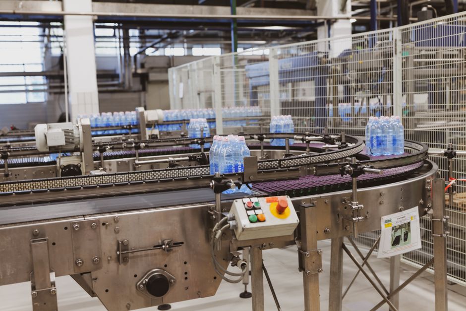 Water bottles being processed on an automated conveyor in a modern factory setting.